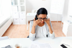 business, overwork, deadline, vision and people concept - tired businesswoman with glasses working at office and rubbing eyes